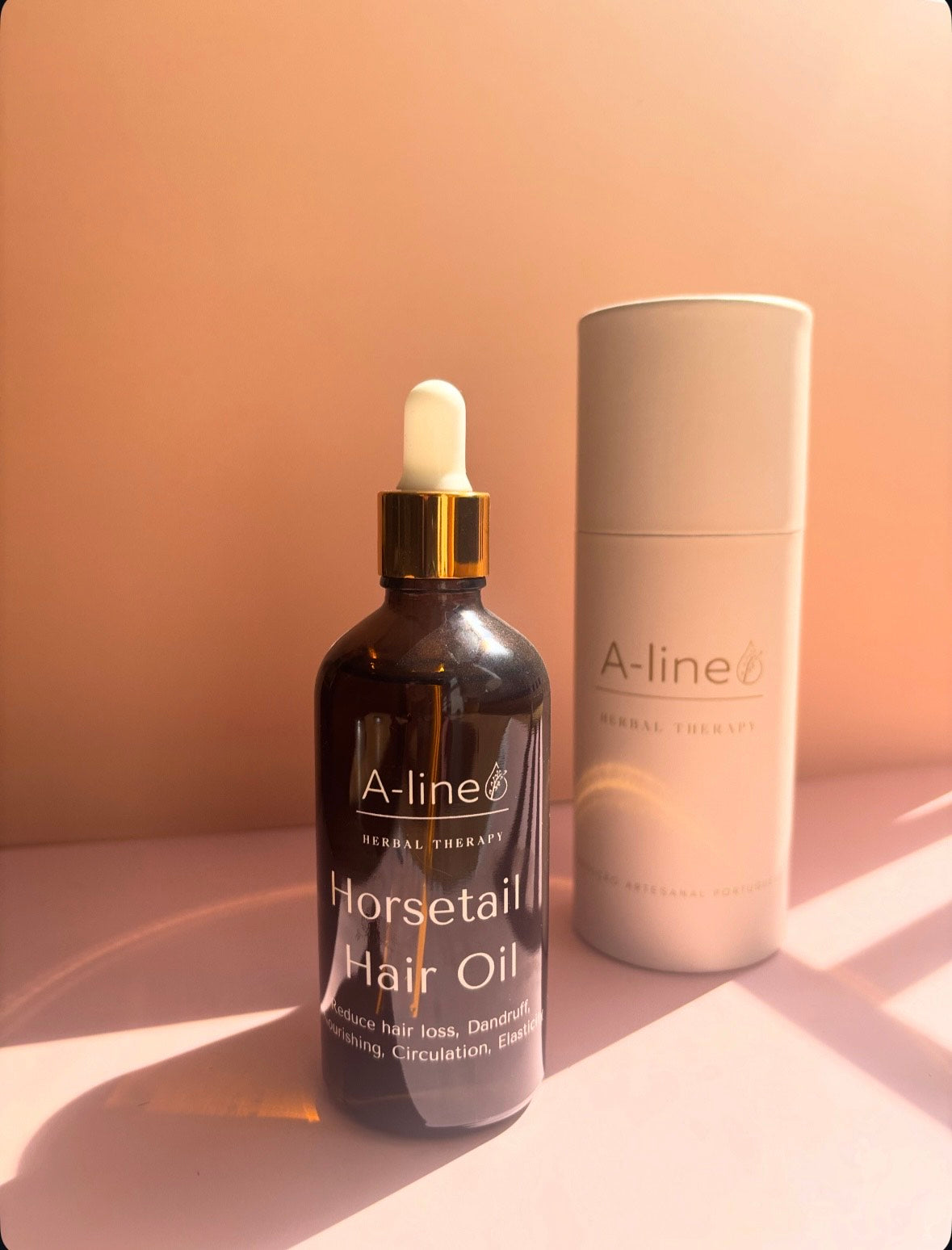 A-Line Horsetail Hair Oil in an amber glass dropper bottle beside its product packaging.